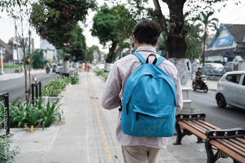 asian young student wearing bag go to the campus walking alone