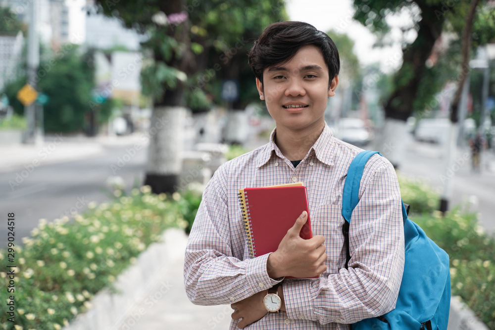 confident young student standing and holding books go to campus confident young student standing and holding books go to campus
