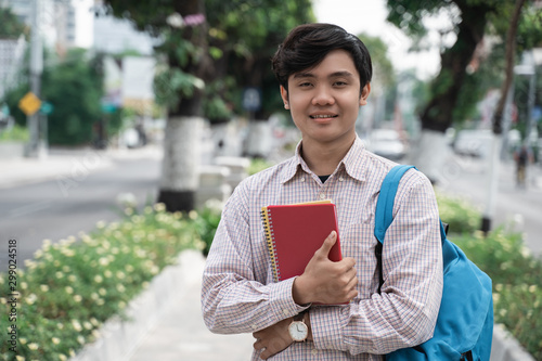confident young student standing and holding books go to campus