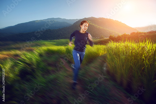 Move-motion style with women trailing running in beautiful light flare on mountains with rice terraces background © sakepaint