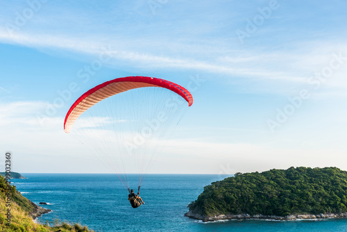 Paragliding Extreme sport, Paraglider flying on the blue sky and white cloud in Summer day at Phuket Sea, Thailand.