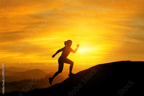 Silhouette of women trailing running in beautiful light flare on mountains