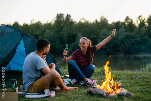 romantic couple on camping by the camping fire playing guitar