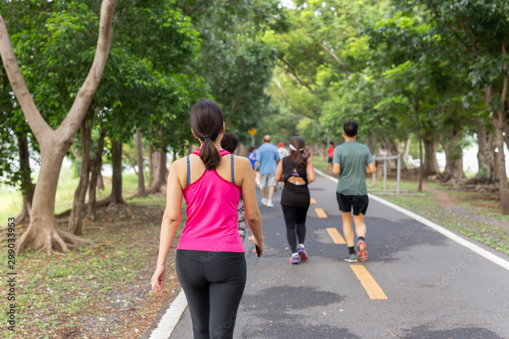 Woman exercise walking in the park with group people in blur background. Woman exercise walking in the park with group people in blur background.