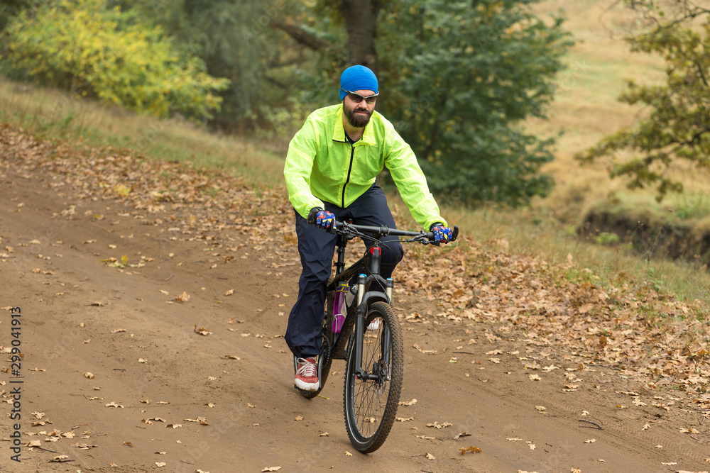 Cyclist in shorts and jersey on a modern carbon hardtail bike with an air suspension fork rides off-road