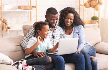 Portrait of happy black family using laptop at home together
