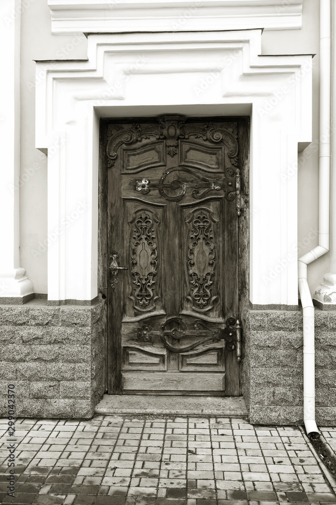 The old wooden door. Ancient antique wooden in an old wall. Ancient decorative wooden door. Historical art style facade of an elite expensive antique door. Wooden background, vintage element The old wooden door. Ancient antique wooden in an old wall. Ancient decorative wooden door. Historical art style facade of an elite expensive antique door. Wooden background, vintage element