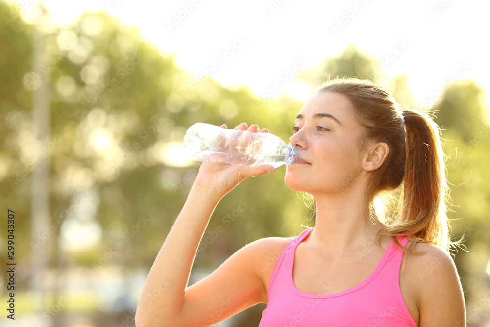 Runner drinking water from a bottle in a park Runner drinking water from a bottle in a park