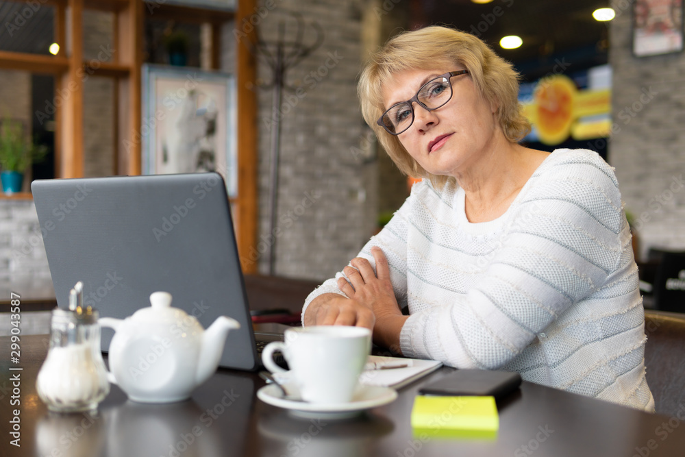 A woman with a laptop works in a cafe, she watches social networks. A woman with a laptop works in a cafe, she watches social networks.