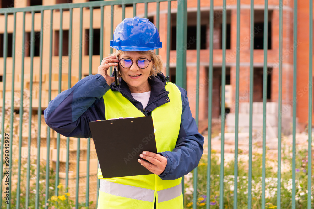 A woman Builder at a construction site inspects a house made of brick A woman Builder at a construction site inspects a house made of brick