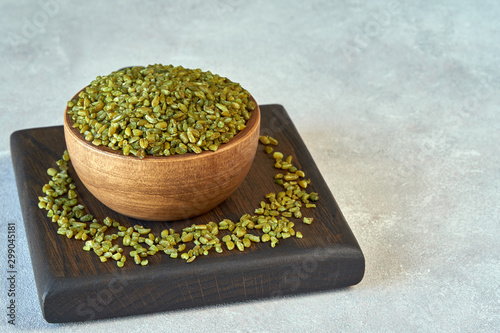 Uncooked cracked freekeh grain in wooden bowl photo