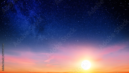 Sunset sky with orange setting sun and red clouds landscape against bright star on black universe background. Wide panorama view of stars in space nature at dark time. Starry night at night wallpaper © vaalaa