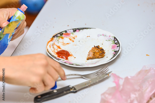 Man eats meat with a knife and fork on an empty plate.