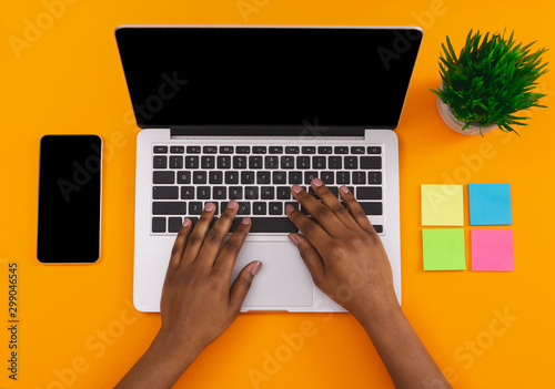 Female using laptop and smartphone with black screen at workplace