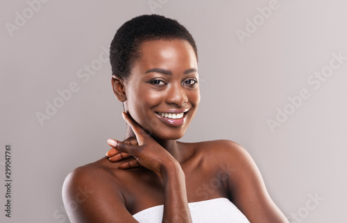Portrait of pretty afro woman touching skin on her neck