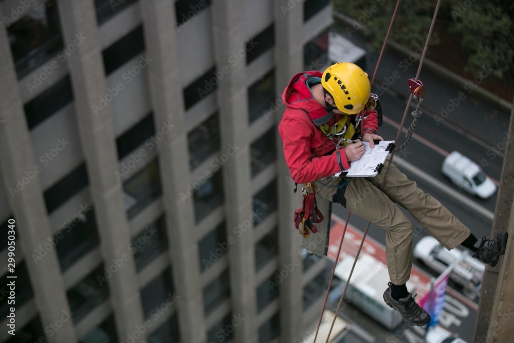 Wide angle pic of male rope access inspector worker working at height