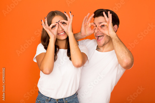 Crazy couple making funny glasses, holding fingers near eyes