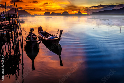 Fishing boats at pier during sunrise with yellow beautiful sky in Andaman sea