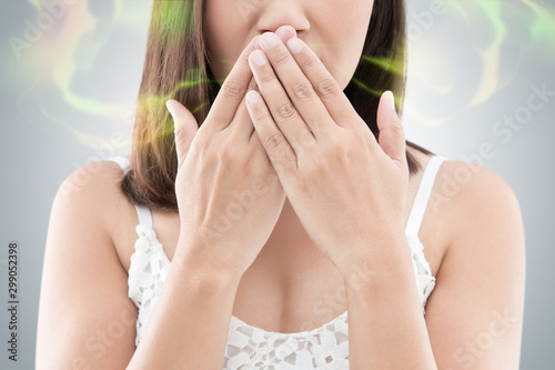 Asian woman in white wear close her mouth against gray background, Bad breath photo
