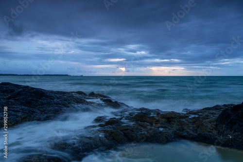 Dramatic seascape sunset with blue cloud and sky and strong wave hits rocks on shore