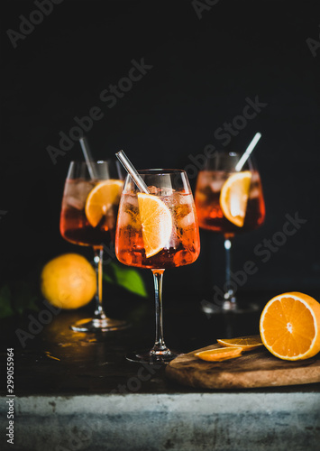 Foto Aperol Spritz aperitif with oranges and ice in glass with eco-friendly glass straw on concrete table, black background, selective focus, copy space
