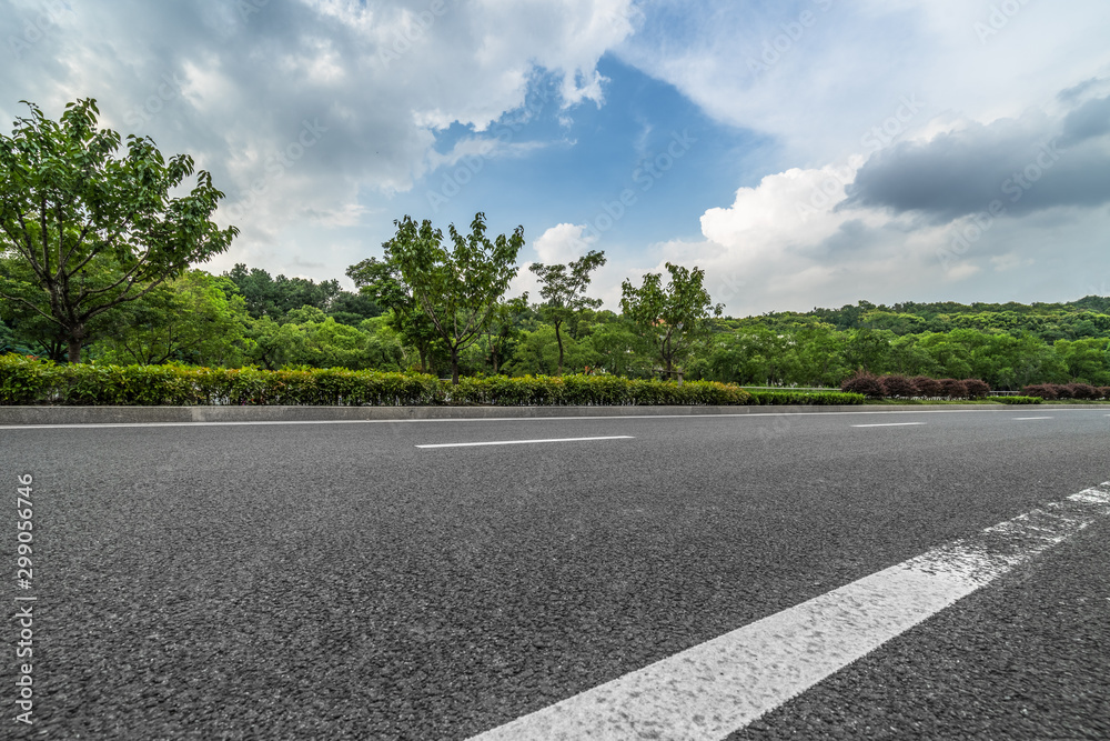 Asphalt road and green trees in the blue sky