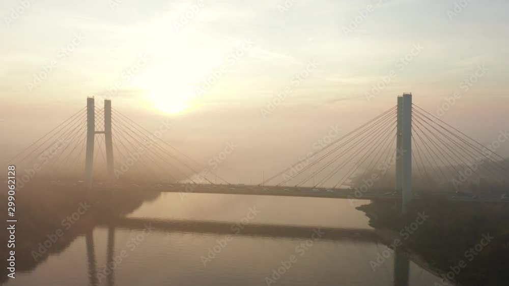 Aerial view Siekierkowski, Bridge with Low Fog. Warsaw. Poland. Drone flies to the bridge in the fog at sunrise. Drone shot at the traffic of vehicle traveling in traffic jam on a bridge over a river. Aerial view Siekierkowski, Bridge with Low Fog. Warsaw. Poland. Drone flies to the bridge in the fog at sunrise. Drone shot at the traffic of vehicle traveling in traffic jam on a bridge over a river.