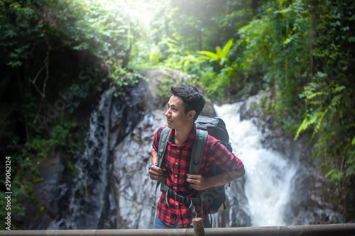 Hiker male standing in front of the waterfall with backpack. travel concept.