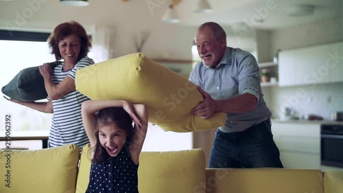 A small girl with senior grandparents indoors having fun. photo