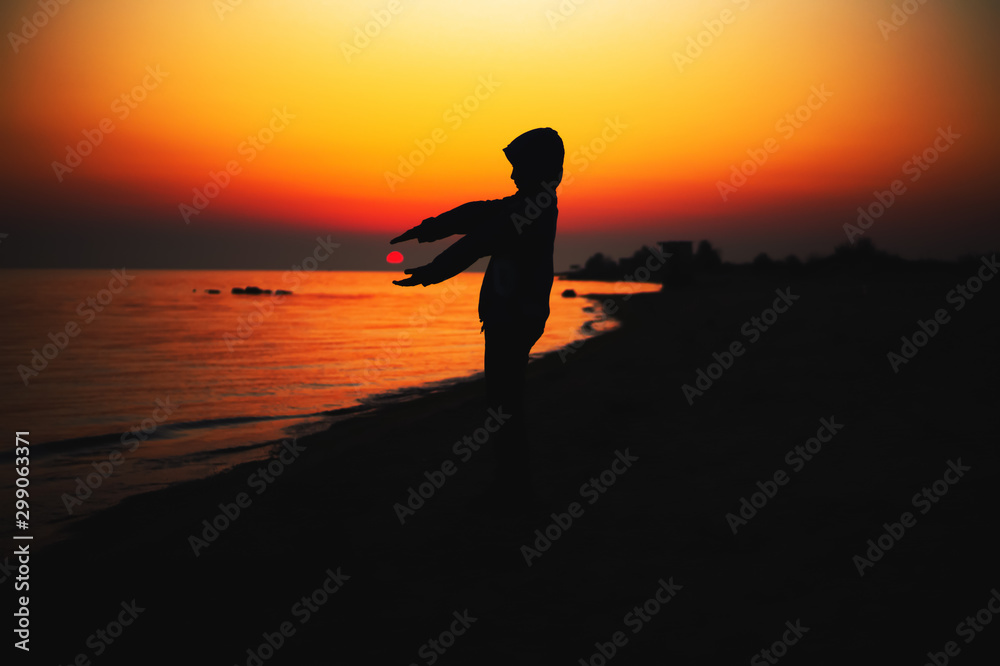 Silhouette of a man holding the sun in his hands at sunset. Landscape background.