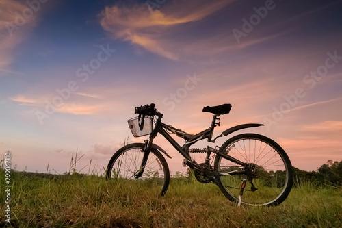 Mountain view even Silhouette a bicycle parking on grass field around with forest, mountain and cloudy sky background, sunset at Thung Salang Luang National Park, Phetchabun, Thailand.