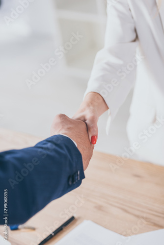 partial view of businessman shaking hands with client in office