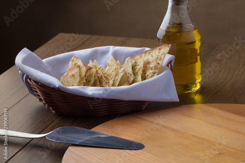 Crostinis served on a wooden table with glass of extra virgin olive oil, steel spatula and wooden cutting board to compose its composition. Typical dish from Italy, widely used in pizzerias photo