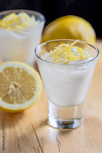 wo glasses with white lemon mousse decorated with zest of lemon. Vertical.