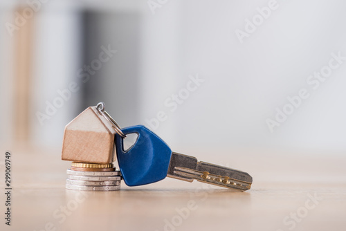 key with toy house trinket on stack of holden and silver coins on wooden table photo