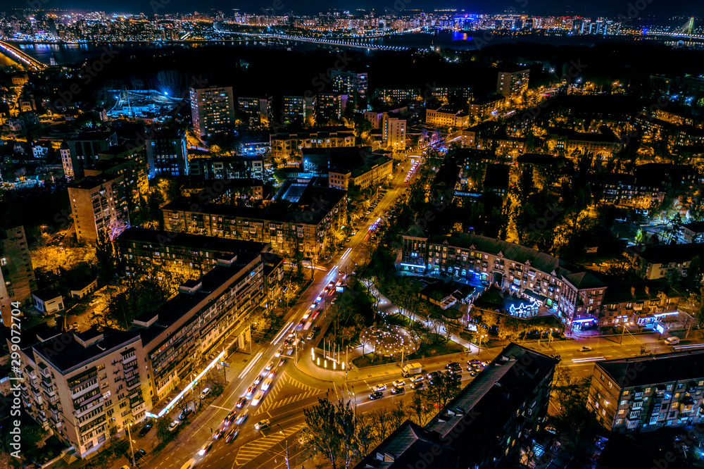 A fabulous New Year's city in blue and yellow neon lights with streets, cars and lights illuminated at night. Beautiful magical city aerial view. Aerial photography.