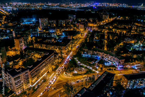 A fabulous New Year s city in blue and yellow neon lights with streets  cars and lights illuminated at night. Beautiful magical city aerial view. Aerial photography.