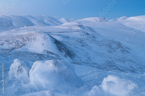 Winter mountain landscape. View of the snowy hills in the evening twilight. The harsh nature of the Arctic. Traveling and hiking to the far north. Golden Ridge, Chukotka, Siberia, Far East of Russia.