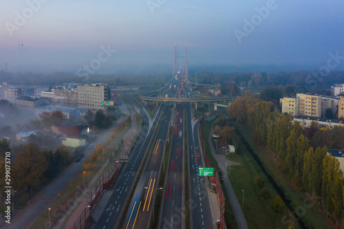 Drone shot of a highway in Warsaw in the morning rush hour, with fog at dusk.  Transport. Poland. Aerial view of a freeway with bridges and junctions at sunrise and fog. 