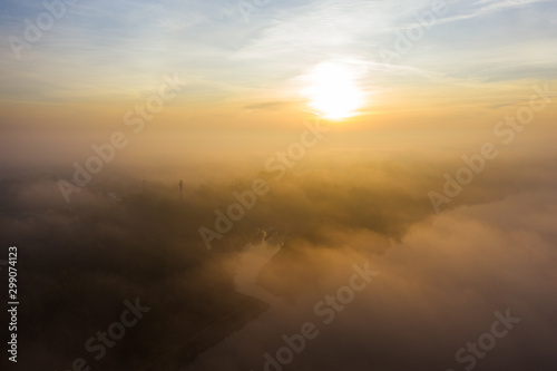 Drone shot above the clouds towards the sun. The sky above the clouds on a sunny morning. Aerial view of low fog over a river at sunrise. 4K Drone shot.