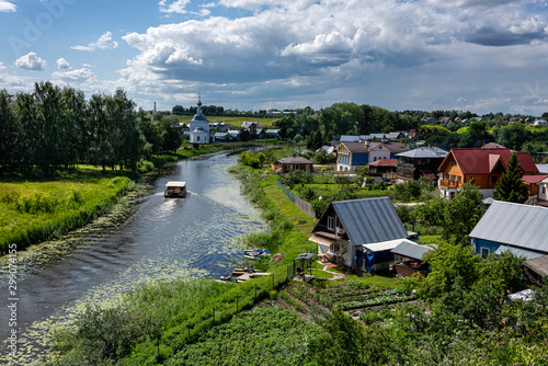 Russia, Vladimir Oblast, Golden Ring,Suzdal: Panorama view with boat on river Kamenka, green riverside and famous old orthodox churches, monasteries, convents in one of the oldest Russian towns.