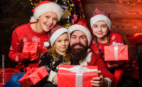 Christmas joy. Christmas tradition. Happy holidays. Parents and children opening christmas gifts. Cheerful family concept. Father Santa claus and mother little daughters christmas tree background