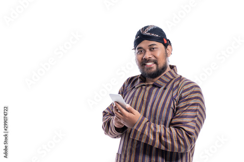 asian man with javanese traditional cloth lurik using smart phone isolated over white