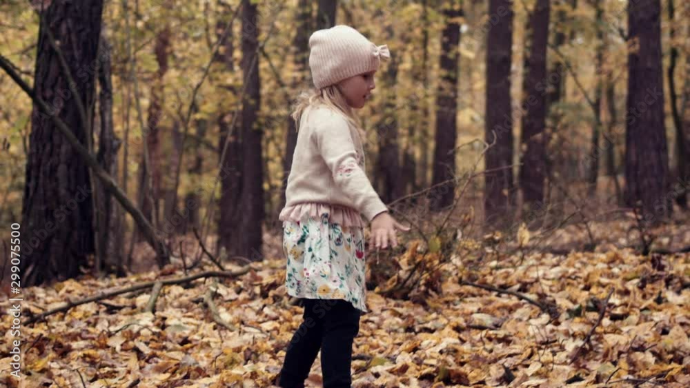 Happy young girl in pink hat plays in fall leaves in golden autumn forest Happy young girl in pink hat plays in fall leaves in golden autumn forest