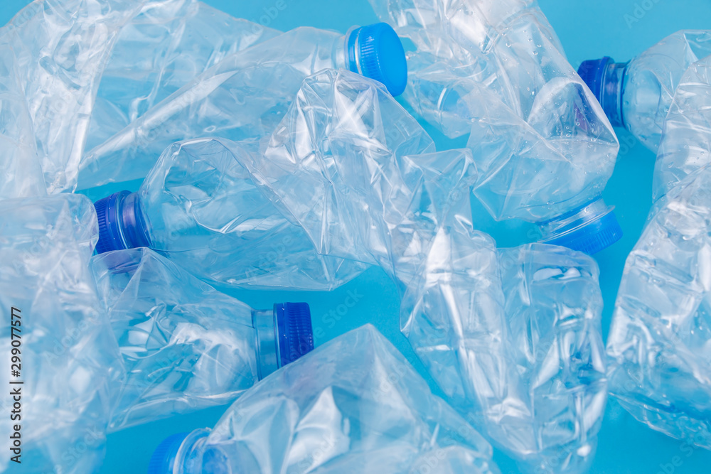 Obraz premium Zużyte plastikowe butelki zgniecione i pogniecione do recyklingu na niebieskim tle. Zanieczyszczenie środowiska i koncepcja recyklingu tła.