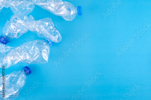 Used plastic bottles crushed and crumpled for recycling on the blue background with copy space. Environment pollution and recycle background concept.