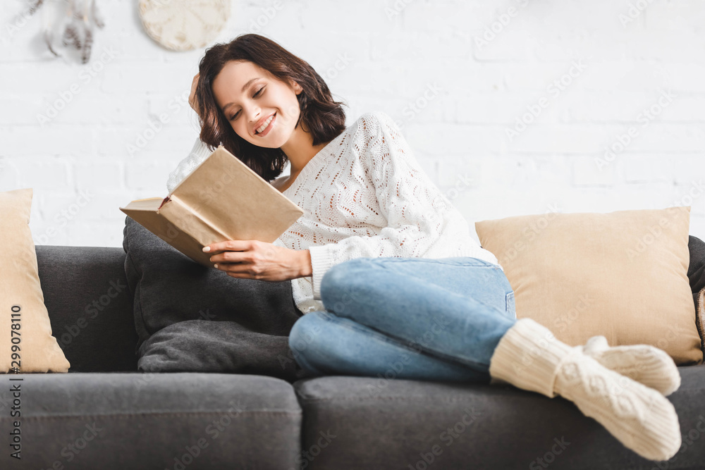 pretty smiling girl reading book on sofa at home pretty smiling girl reading book on sofa at home