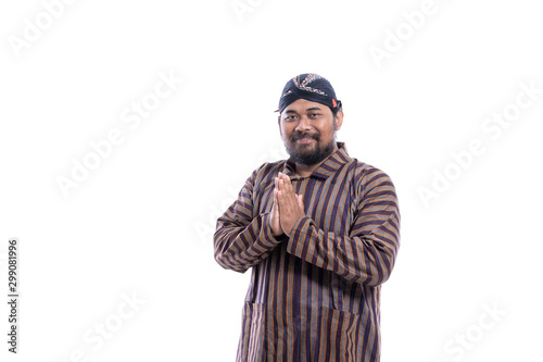 asian man with javanese traditional cloth lurik greeting and smiling to camera