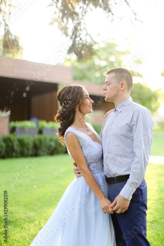 Caucasian bride dancing with groom in park and wearng white dress. photo