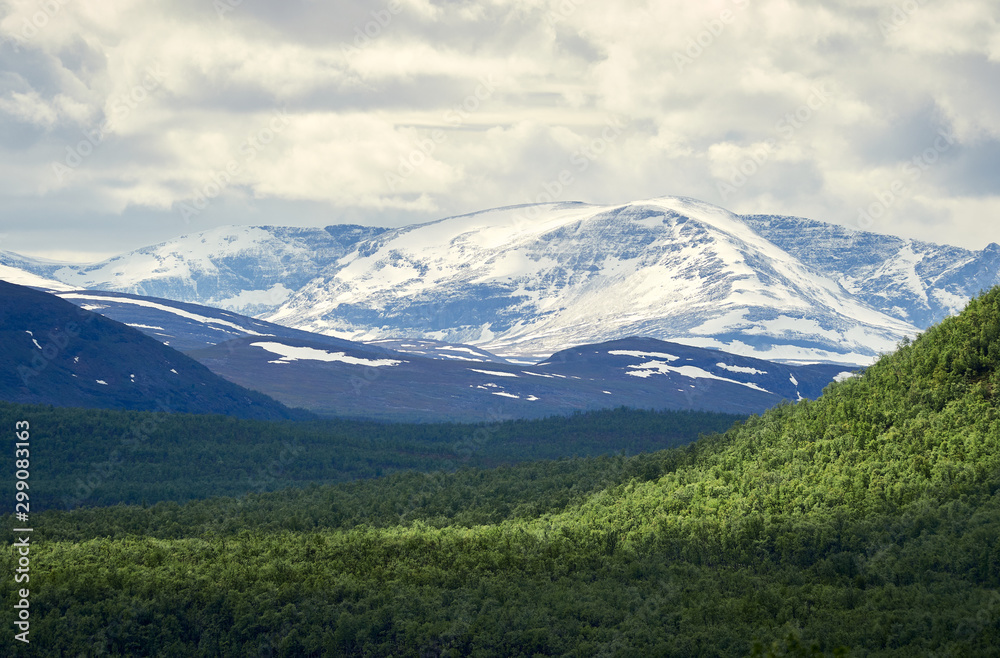 Mointains in Norway seen from Kilpisjarvi, Finland. Snowy peaks on a partly cloudu summer day.
